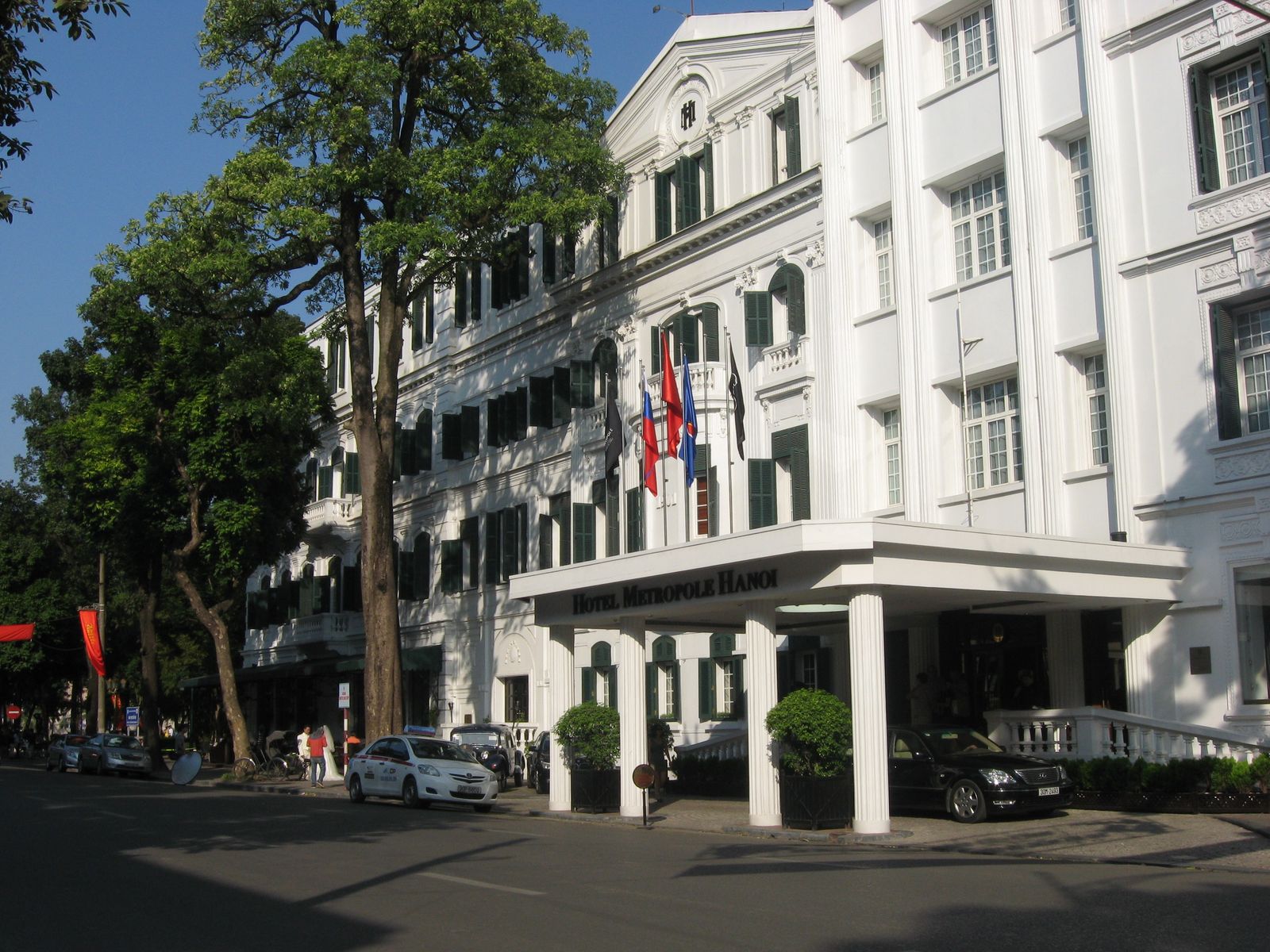 The white facade, green shutters and covered entrance of the Metropole hotel in Hanoi.