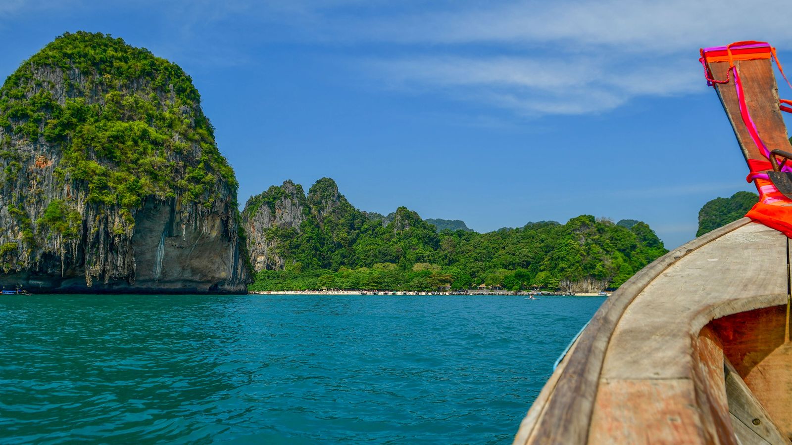 The view from a wooden longtail boat approaching limestone islands in the blue-green water off Krabi.