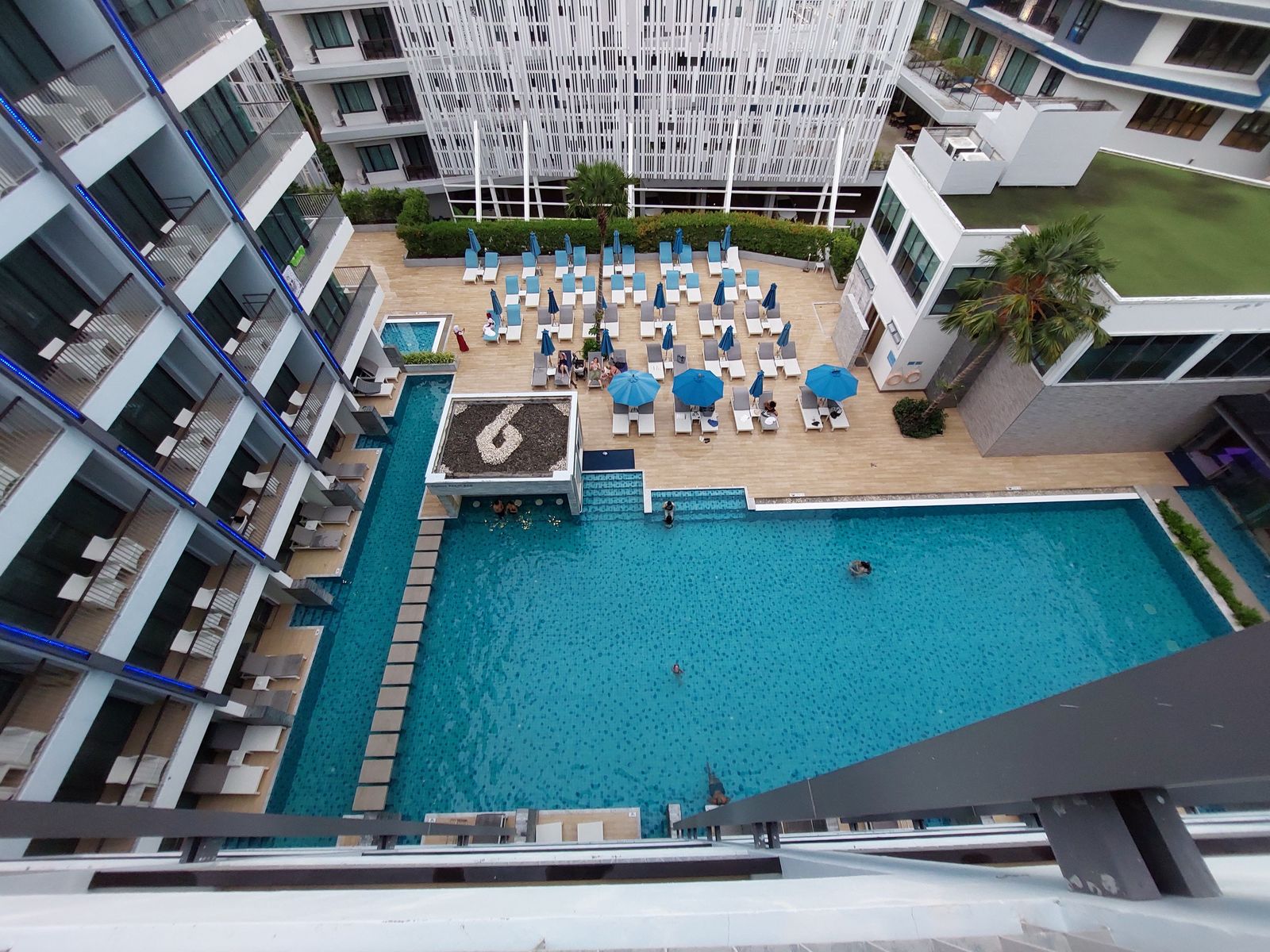 A resort swimming pool and sun loungers sit between guest-room balconies in Krabi, Thailand.