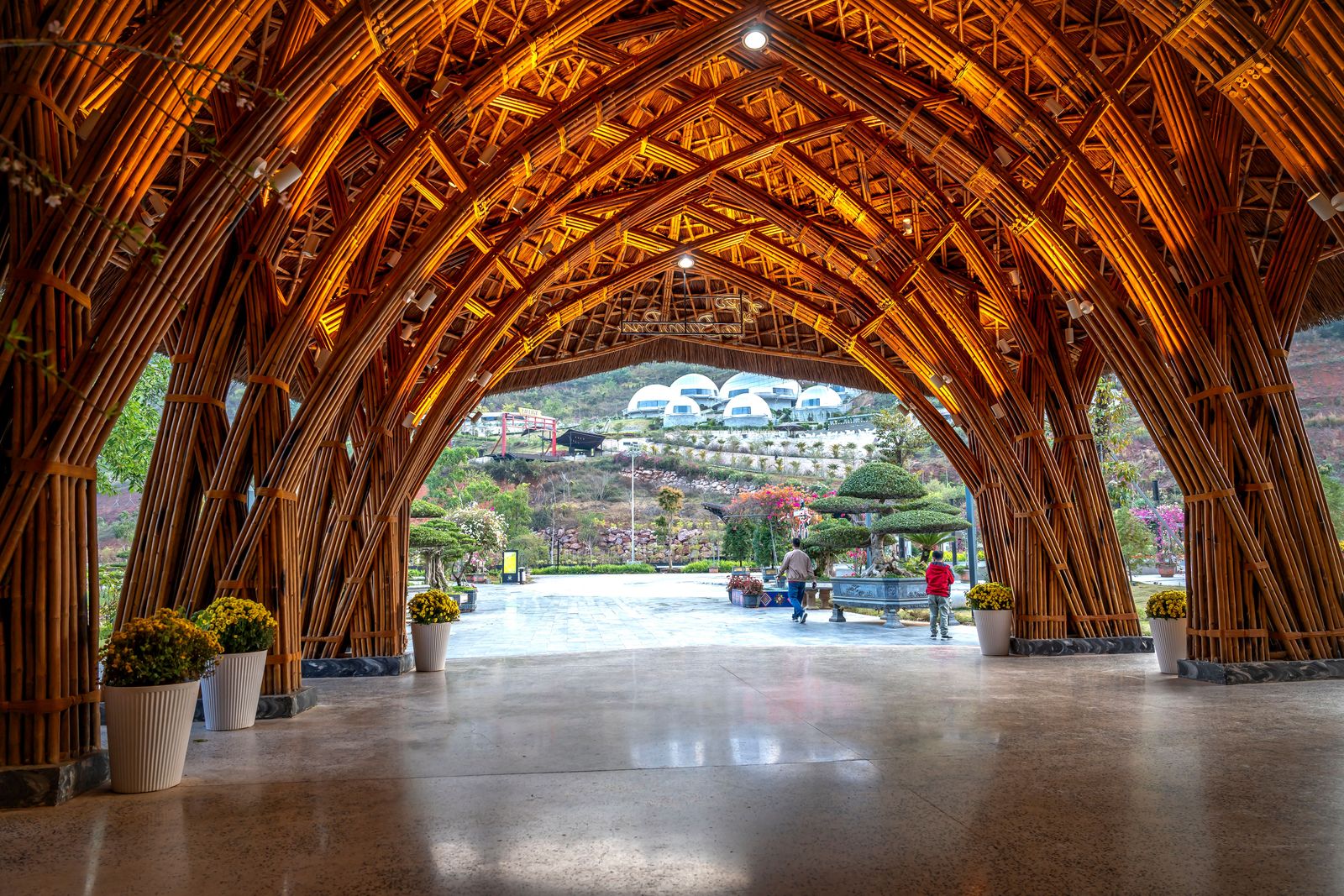 A vaulted bamboo pavilion frames a garden and the surrounding landscape at a resort in Ninh Binh.