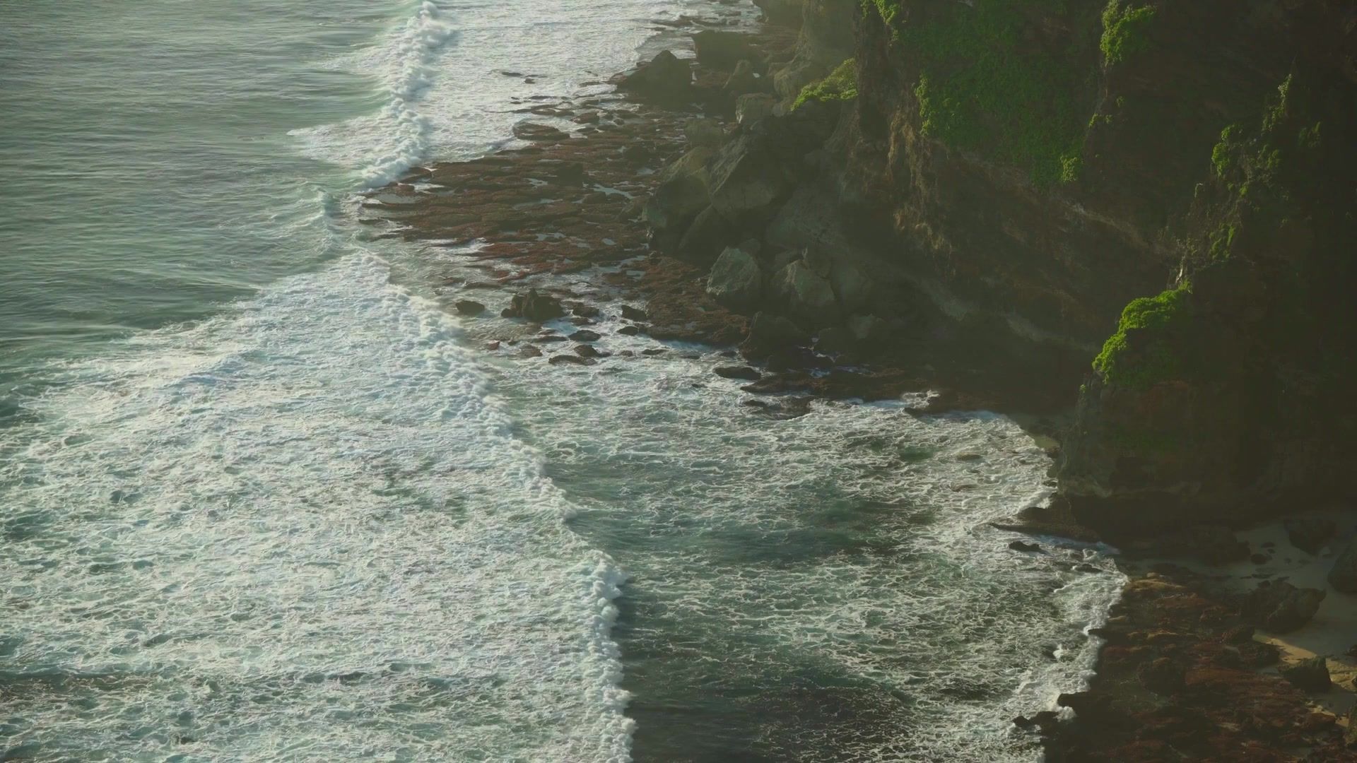 Waves meet the green cliffs along Bali’s Uluwatu coast.